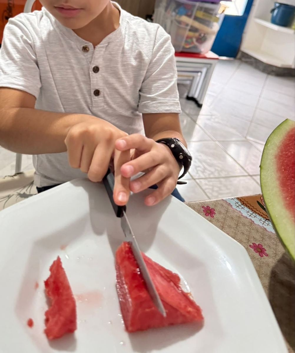 Criança desenvolvendo habilidades de vida diária cortando fruta